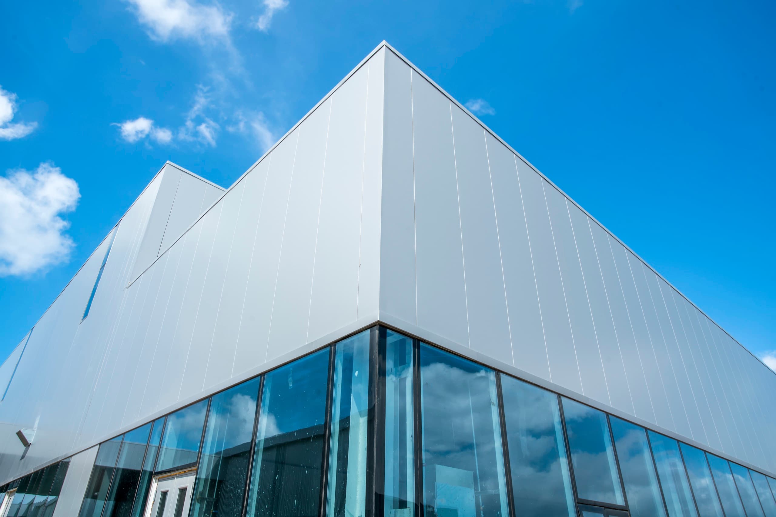 Low-angle view of a white clad industrial facility against open sky